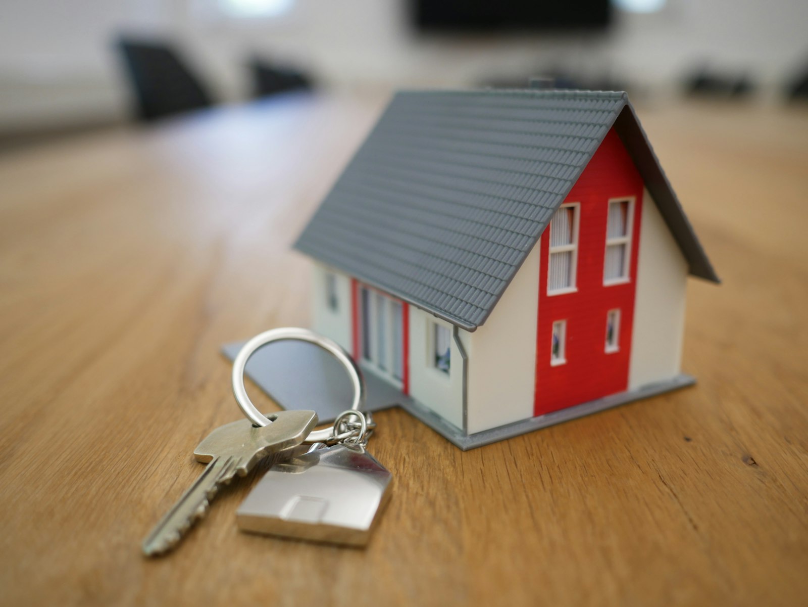 Llaves de una vivienda junto a una maqueta de casa sobre una mesa de madera