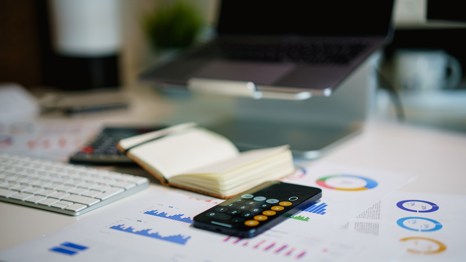 Escritorio con una calculadora, un teléfono con gráficos financieros y un cuaderno