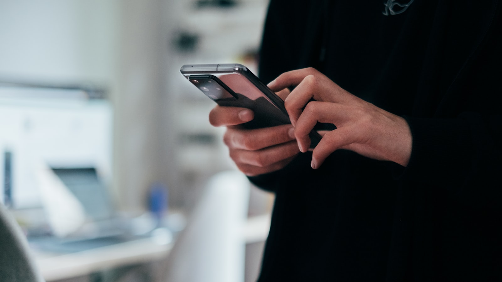 Manos escribiendo en un smartphone en una oficina